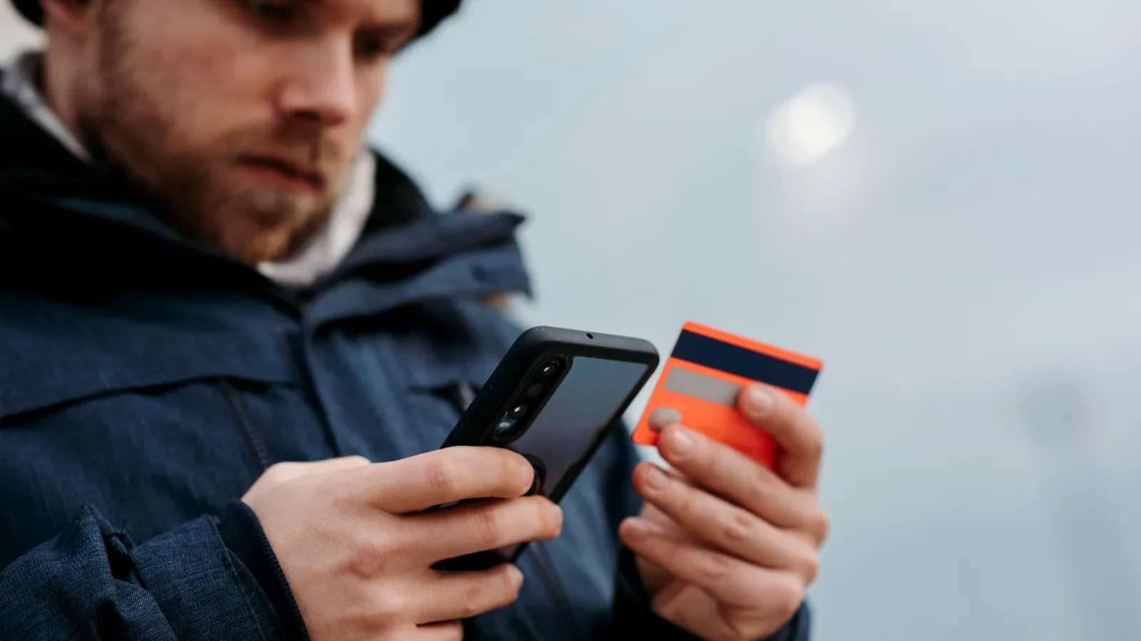 Muž platící za online nákup pomocí telefonu a platební karty.